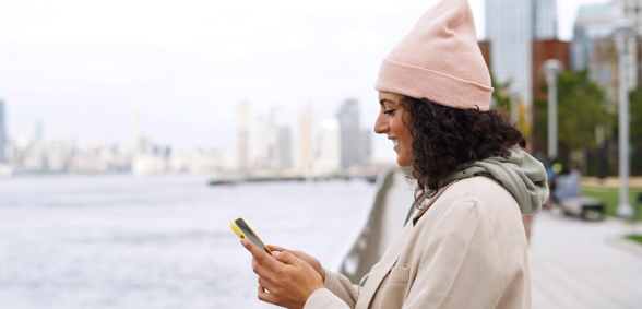 Person looking at phone near river working on upcoming multi-location SEO strategy